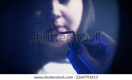 Young woman summoning the Queen of Spades while painting a staircase with lipstick on a mirror