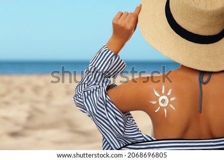 Young woman with sun protection cream on sandy beach, space for text