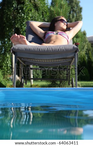 young woman sunbathing by the pool