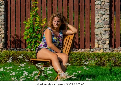 Young Woman Sunbathing While Sitting On A Chair In The Garden.