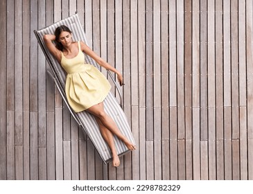 Young woman, sunbed and luxury summer resort, vacation or holiday to relax outdoors and lounge in the spring sun. Girl, sleeping on tanning bed and top view of modern wood deck in background