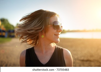 Young woman in sunglasses enjoying summer breeze at sunset beach. Closeup, shallow DOF. - Powered by Shutterstock