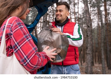 Young Woman In Sunglasses And Happy Man Holding Trash Bag In Woods 