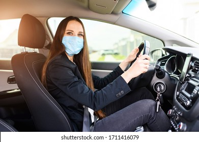 Young Woman With Surgery Protective Mask On Her Face Is Driving Car. Virus Protection, Keep Yourself In Safety