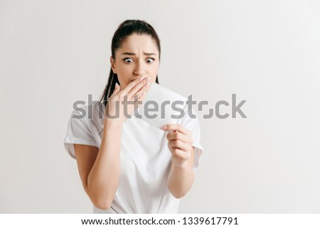 Young woman with a surprised unhappy expression lost a bet on studio background. Human facial emotions and betting concept. Trendy colors.
