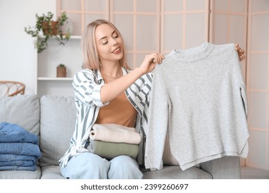 Young woman with sweater and folded clothes at home