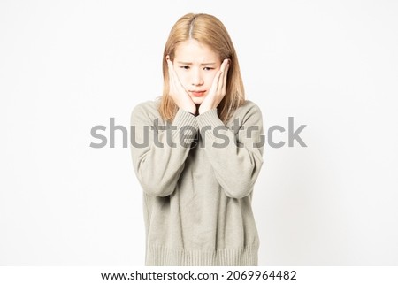 A young woman in a sweater with a toothache and a hand on her cheek