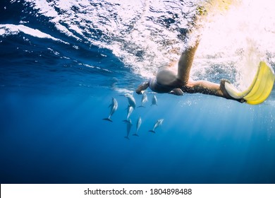 Young woman swim underwater with spinner dolphins in blue ocean at Mauritius