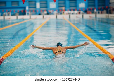 Young woman swimmer swims in swimming pool