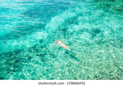 Young Woman Swimming In The Beautiful Blue Sea. Overhead View. Aerial Shot.