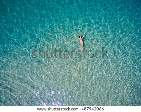 Young woman swimming in the blue sea. Top view. White beach, Phuket, Thailand.