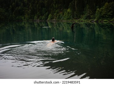 A Young Woman Swimming In A Lake On A Smoky Evening. Wild Swimming.