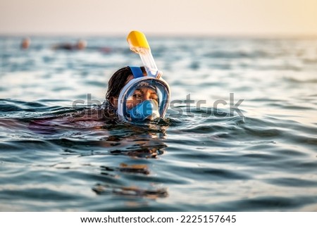 Young woman swimming in the sea with modern snorkeling gear. Full face snorkeling mask. Tropical sea sport activity. Summer vacation in exotic island