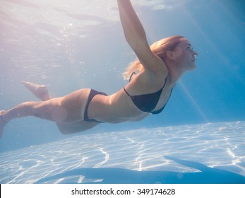 Young Woman Swimming Underwater In The Swimming Pool