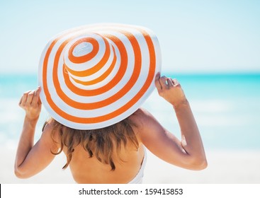 Young Woman In Swimsuit Beach Hat Looking Into Distance . Rear View