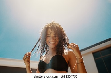 Young woman in swimsuit having great time by swimming pool outdoors