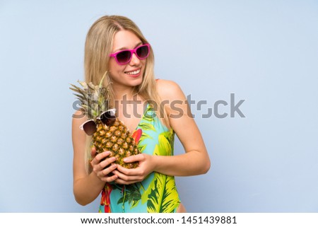 Young woman in swimsuit holding a pineapple with sunglasses