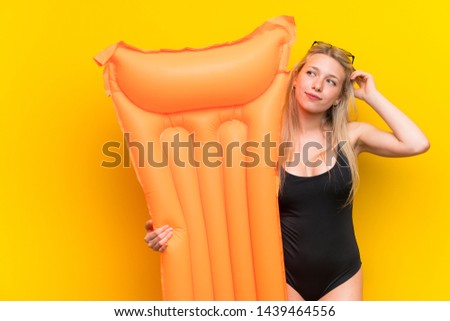 Young woman in swimsuit over yellow background thinking an idea