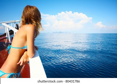 Young woman in swimsuit standing on yacht at sunny day and looking to a sea - Powered by Shutterstock