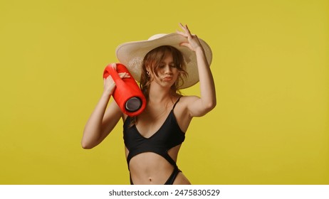 Young woman in swimsuit and stylish hat with music speaker dances lively at camera. Travel, summertime vacation, beach leisure concept. - Powered by Shutterstock