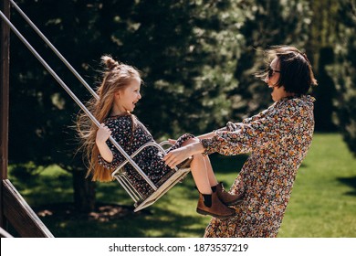 Young woman swinging with her daughter in the backyard - Shutterstock ID 1873537219