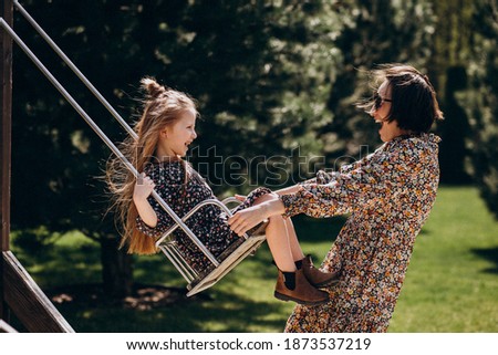 Young woman swinging with her daughter in the backyard
