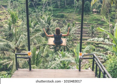 Young Woman Swinging In The Jungle Rainforest Of Bali Island, Indonesia. Swing In The Tropics.