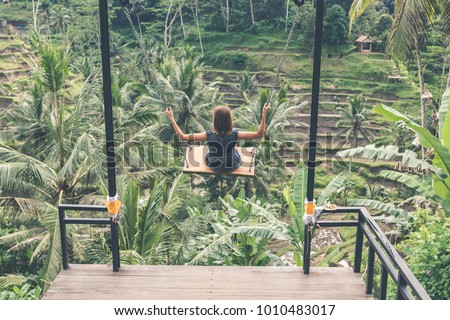 Young woman swinging in the jungle rainforest of Bali island, Indonesia. Swing in the tropics.