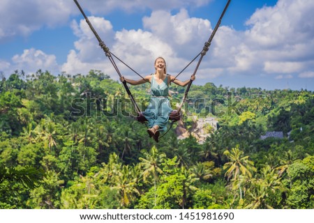 Young woman swinging in the jungle rainforest of Bali island, Indonesia. Swing in the tropics. Swings - trend of Bali