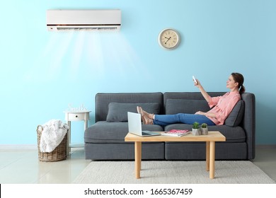 Young woman switching on air conditioner at home - Shutterstock ID 1665367459