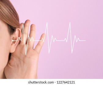 Young woman with symptom of hearing loss on color background. Medical test