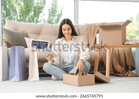 Young woman with tablet computer and ordered online shoes at home