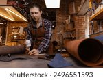 Young woman tailor cutting brown leather patterns in atelier workshop. Concept small business footwear industry, shoemaker.