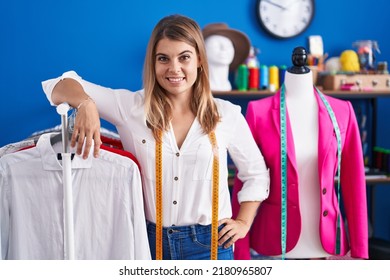 Young Woman Tailor Smiling Confident Leaning On Clothes Rack At Sewing Studio