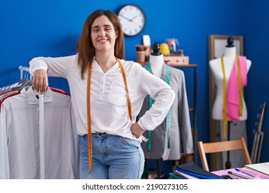 Young Woman Tailor Smiling Confident Leaning On Clothes Rack At Sewing Studio