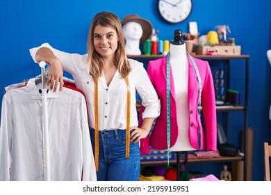 Young Woman Tailor Smiling Confident Leaning On Clothes Rack At Sewing Studio