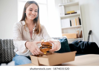 Young Woman With Take Away Hamburger At Home, Coronavirus And Food Delivery Concept.