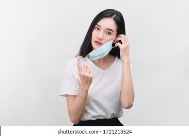 Young Woman Take Off Protective Mask. Female In White T-shirt And Blue Medical Mask. End Of Quarantine. Coronavirus Theme