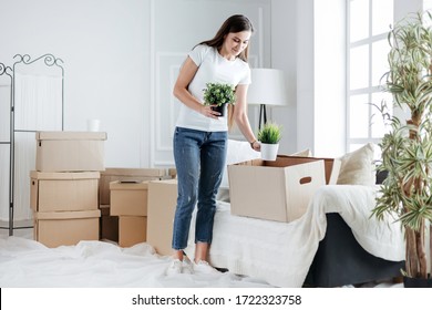 young woman takes her favorite plants out of a cardboard box - Powered by Shutterstock