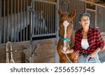 Young woman takes horse on leash for walk from stables