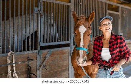 Young woman takes horse on leash for walk from stables - Powered by Shutterstock