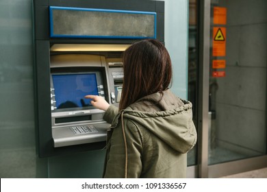 A young woman takes money from an ATM. Grabs a card from the ATM. Finance, credit card, withdrawal of money.