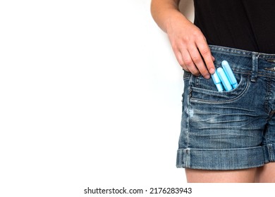 A young woman takes a tampon out of the pocket of her jean shorts, close-up on white background - Shutterstock ID 2176283943