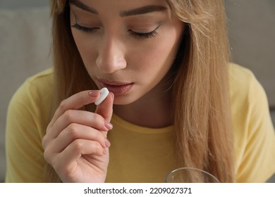 Young Woman Taking Abortion Pill On Light Background, Closeup