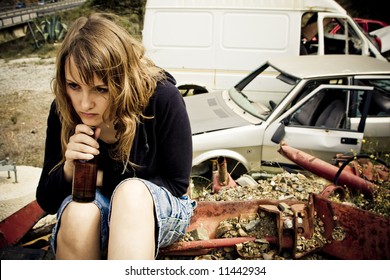 Young woman taking beer in the scrapyard