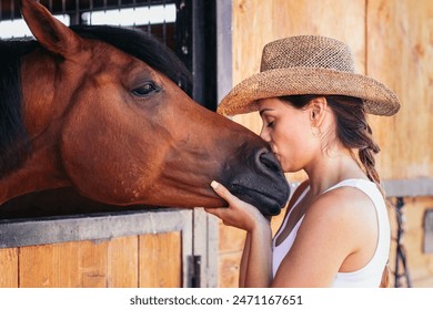 Young woman taking care of her horse in the stable. The horse appears calm and relaxed, while the caregiver provides it with attention and care. - Powered by Shutterstock