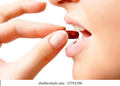 Young Woman Taking Dark Red Pill. Isolated On White. Closeup.