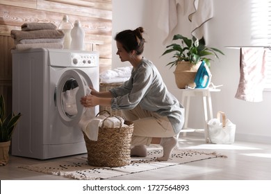 Young Woman Taking Laundry Out Of Washing Machine At Home