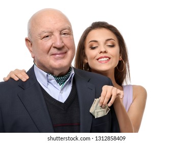Young woman taking money from senior man's pocket on white background. Marriage of convenience
