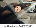 Young woman is taking a nap on a comfortable sofa in the afternoon sun, enjoying a moment of peace and quiet in her living room